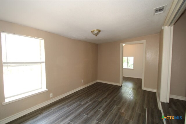 spare room with plenty of natural light and dark hardwood / wood-style floors