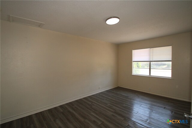 empty room featuring a textured ceiling and dark hardwood / wood-style floors