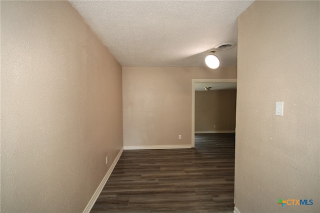 empty room with dark hardwood / wood-style flooring and a textured ceiling