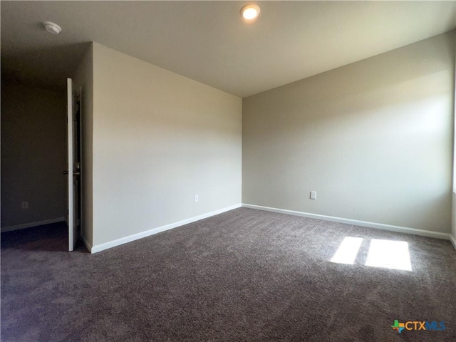 empty room with baseboards and dark carpet