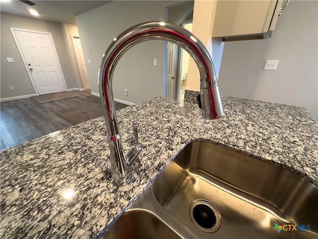 details with dark stone counters, wood finished floors, baseboards, and a sink