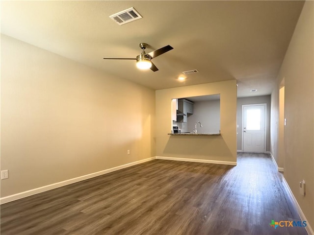 unfurnished living room with a ceiling fan, visible vents, dark wood-style flooring, and baseboards