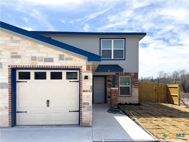 view of front facade featuring stone siding, an attached garage, concrete driveway, and fence