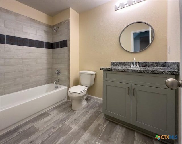 bathroom featuring wood finish floors, toilet, shower / bathtub combination, baseboards, and vanity
