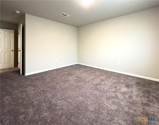 empty room featuring visible vents, dark carpet, and baseboards