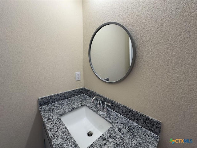 bathroom with vanity and a textured wall