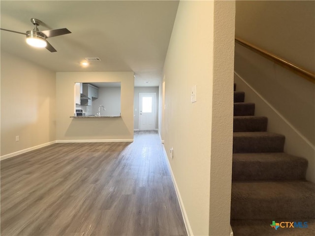 interior space featuring visible vents, baseboards, ceiling fan, dark wood finished floors, and stairs