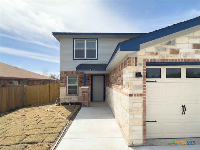 doorway to property with an attached garage, fence, brick siding, and stone siding