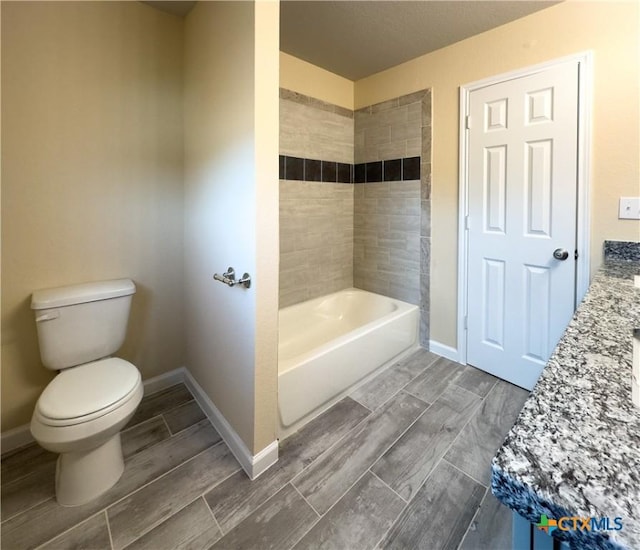 bathroom featuring wood finish floors, baseboards, and toilet