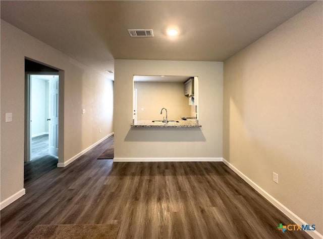 interior space featuring a sink, visible vents, baseboards, and dark wood finished floors