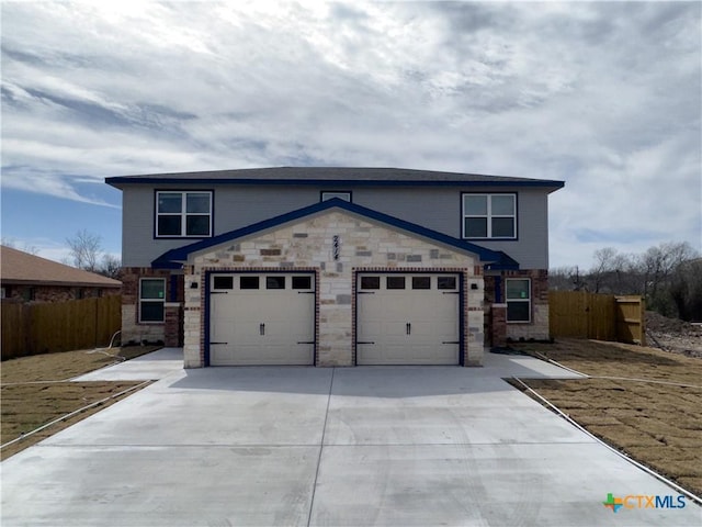 view of front facade with concrete driveway, a garage, fence, and stone siding