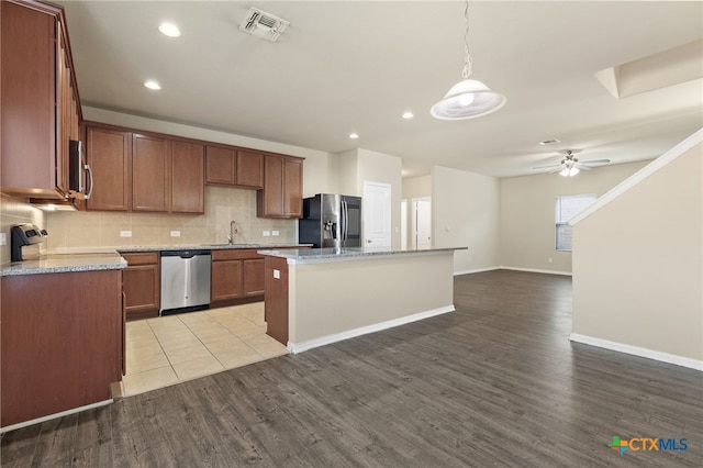 kitchen with decorative backsplash, stainless steel appliances, light hardwood / wood-style floors, and a kitchen island