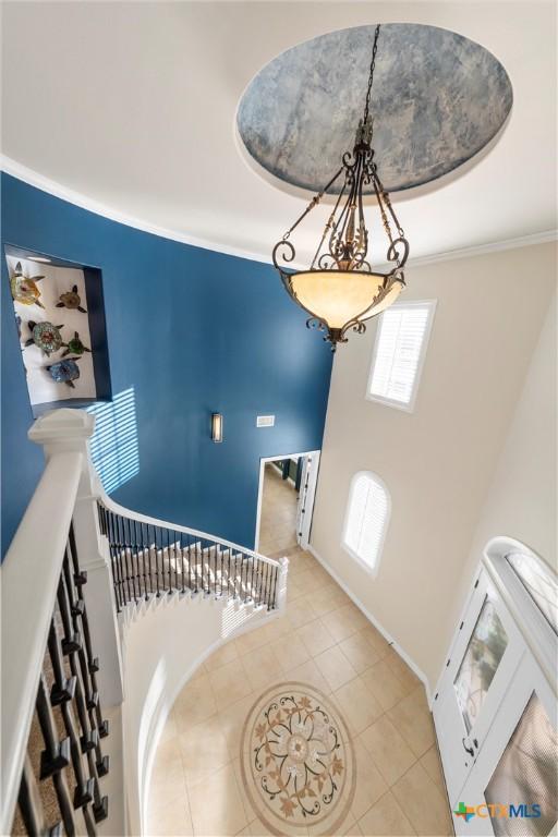 tiled foyer entrance with a tray ceiling and ornamental molding