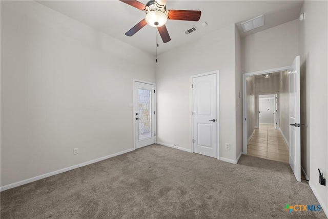 unfurnished bedroom with light carpet, a towering ceiling, and ceiling fan