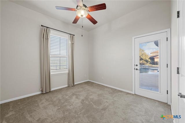 spare room with light carpet, a ceiling fan, and baseboards