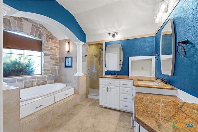 full bath featuring a bath, vanity, a shower stall, and decorative columns