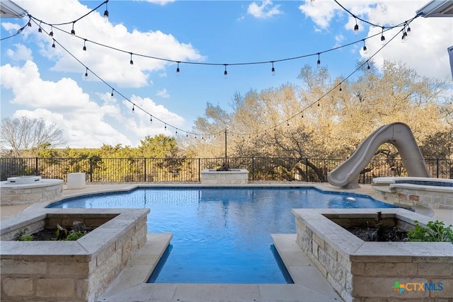 view of swimming pool with an in ground hot tub, a water slide, and an outdoor fire pit