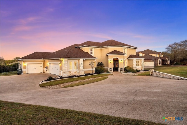 mediterranean / spanish-style house featuring stucco siding, an attached garage, central AC unit, driveway, and a front lawn