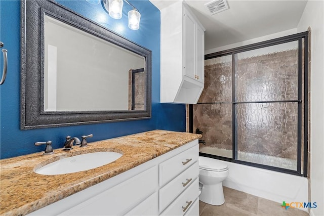 bathroom featuring toilet, vanity, visible vents, combined bath / shower with glass door, and tile patterned floors