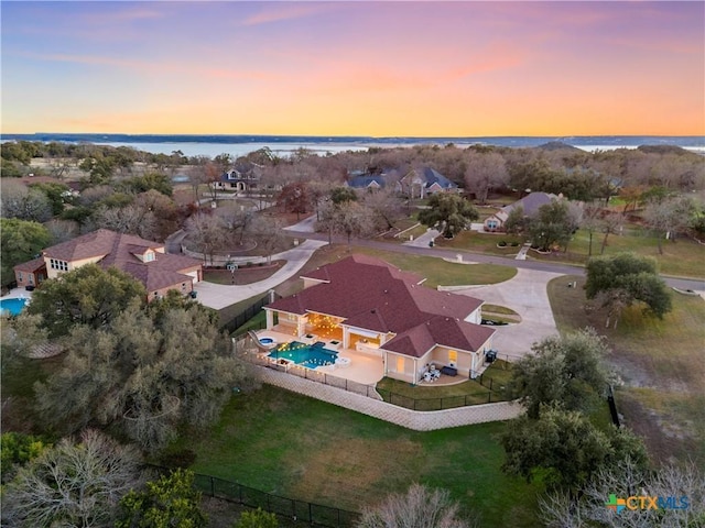 aerial view at dusk featuring a water view