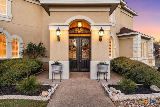 exterior entry at dusk featuring stucco siding