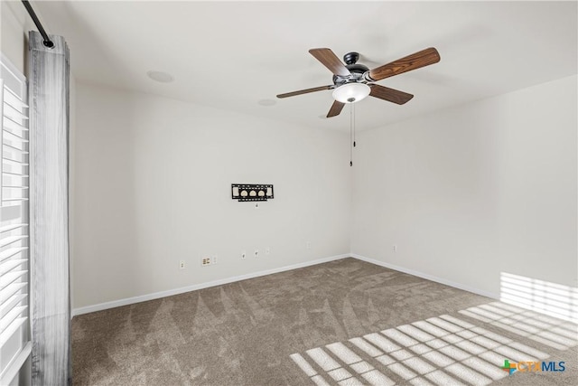 carpeted empty room with ceiling fan and baseboards