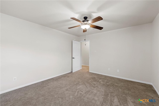 carpeted empty room featuring a ceiling fan and baseboards