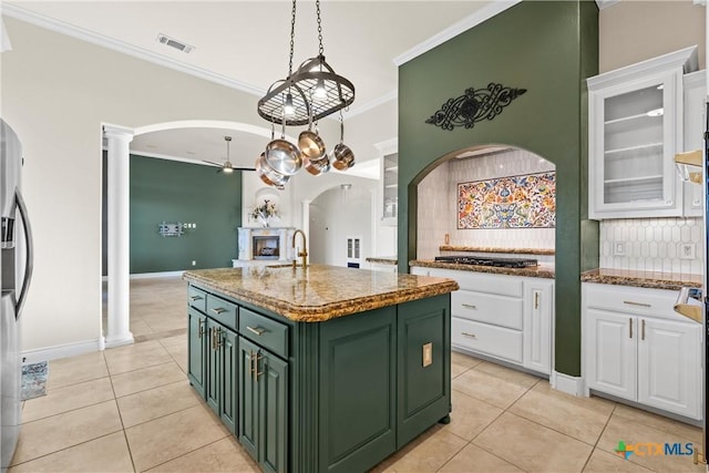 kitchen with white cabinets, backsplash, a center island with sink, and crown molding