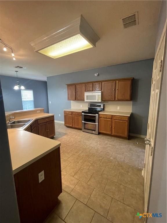 kitchen with pendant lighting, track lighting, double oven range, and sink