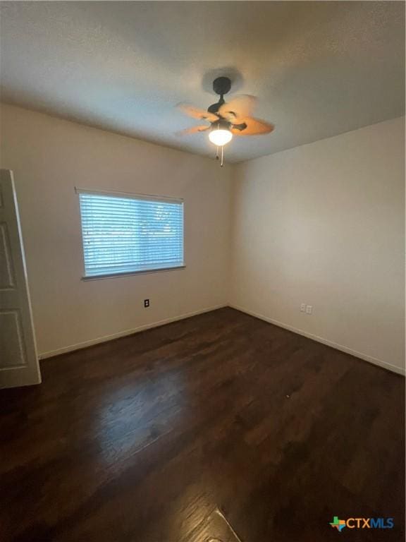 spare room with dark hardwood / wood-style floors and ceiling fan