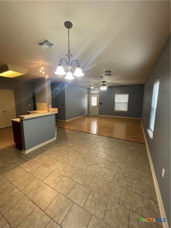 kitchen featuring a kitchen island, light tile patterned flooring, ceiling fan with notable chandelier, and pendant lighting