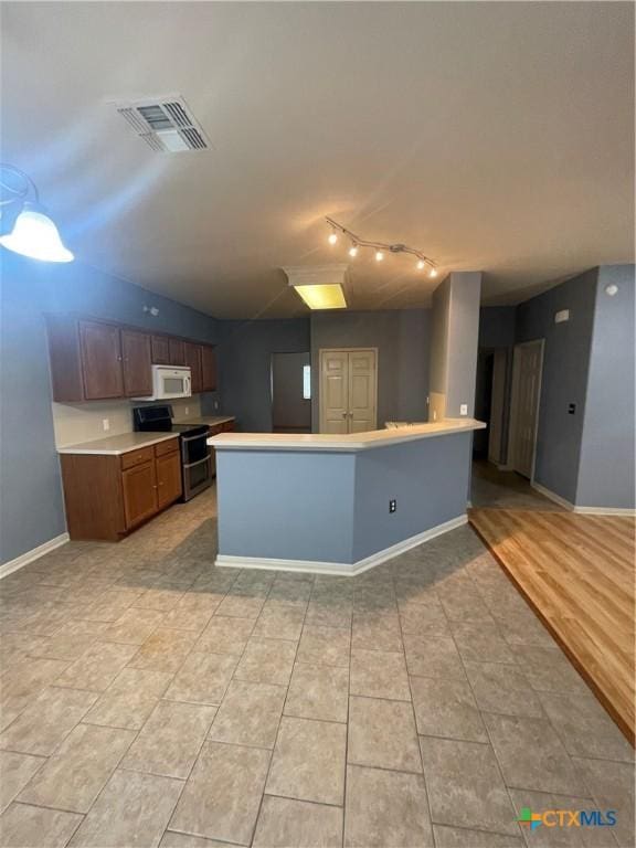 kitchen with double oven range, light tile patterned floors, and a kitchen island