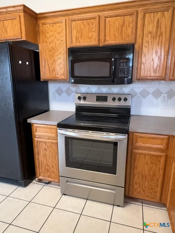 3601 Armstrong County Ct, Killeen, TX 76549 - kitchen featuring black appliances, light tile patterned flooring, brown cabinetry, and backsplash