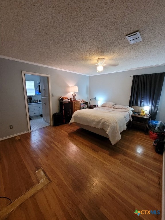 bedroom with visible vents, ornamental molding, wood finished floors, ceiling fan, and a textured ceiling