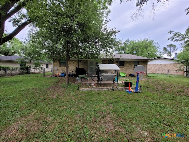 back of property featuring a lawn, a patio, fence, and brick siding