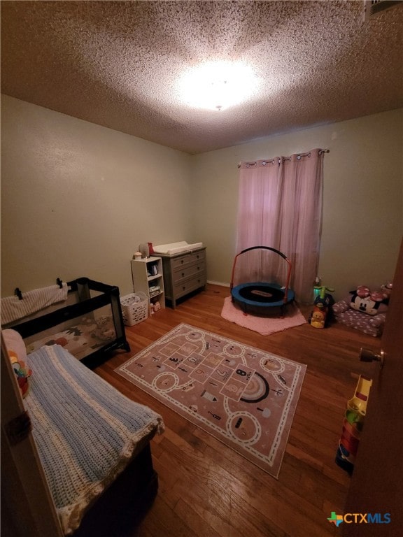 bedroom with a textured ceiling and wood finished floors