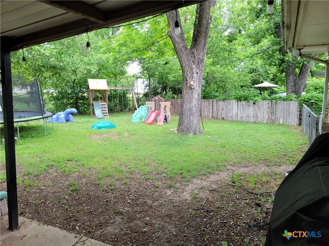 view of yard with a playground, a fenced backyard, and a trampoline