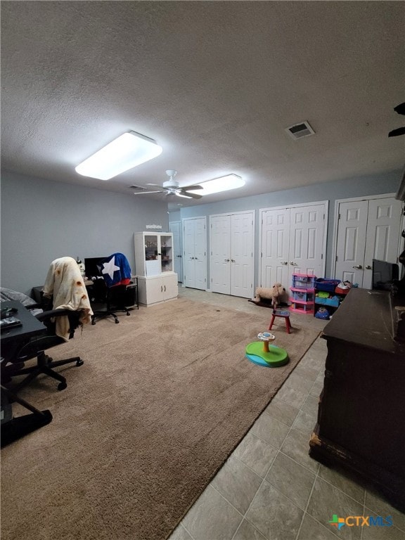 playroom featuring a textured ceiling, visible vents, ceiling fan, and tile patterned floors