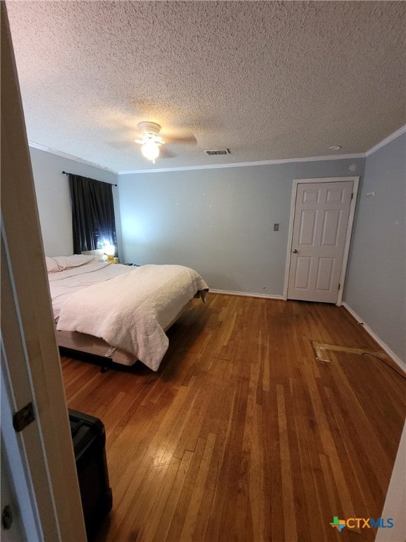 bedroom with ceiling fan, a textured ceiling, visible vents, wood-type flooring, and ornamental molding