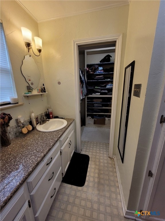 bathroom featuring crown molding, a walk in closet, tile patterned floors, and vanity