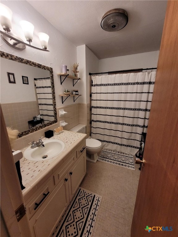 bathroom featuring vanity, a shower with shower curtain, toilet, and tile walls