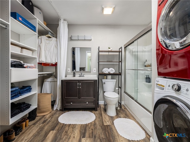 415 Brooks Mill Rd, Bertram, TX 78605 - bathroom featuring stacked washer / drying machine, wood finished floors, vanity, and bath / shower combo with glass door