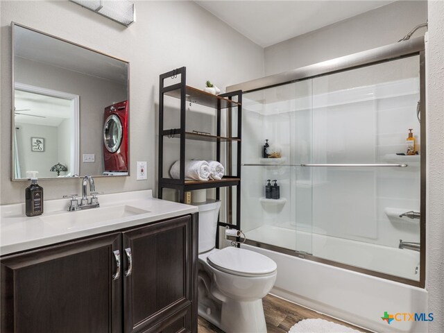 415 Brooks Mill Rd, Bertram, TX 78605 - bathroom featuring stacked washer / dryer, wood finished floors, vanity, and shower / bath combination with glass door