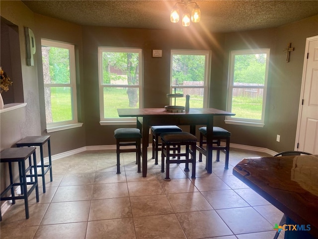 dining room with light tile patterned floors, baseboards, and a textured ceiling