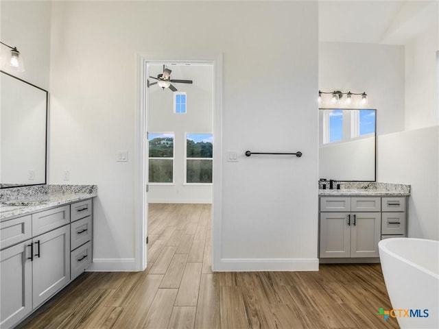 bathroom with ceiling fan, vanity, a bathtub, and a wealth of natural light