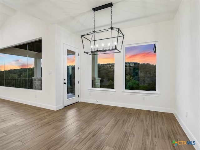 unfurnished dining area featuring wood-type flooring and a notable chandelier