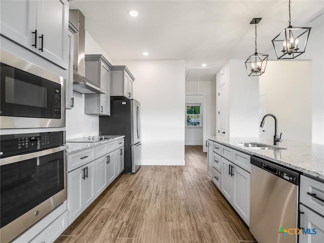 kitchen with black appliances, wall chimney exhaust hood, sink, gray cabinets, and light stone counters