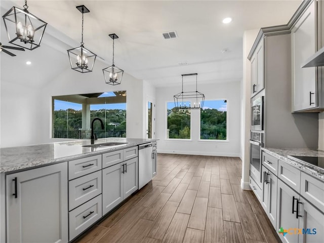 kitchen with decorative light fixtures, light stone countertops, sink, and stainless steel appliances