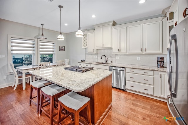 kitchen featuring a kitchen island, white cabinetry, pendant lighting, and stainless steel appliances