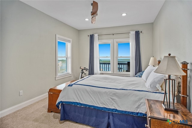 bedroom with a water view and light carpet